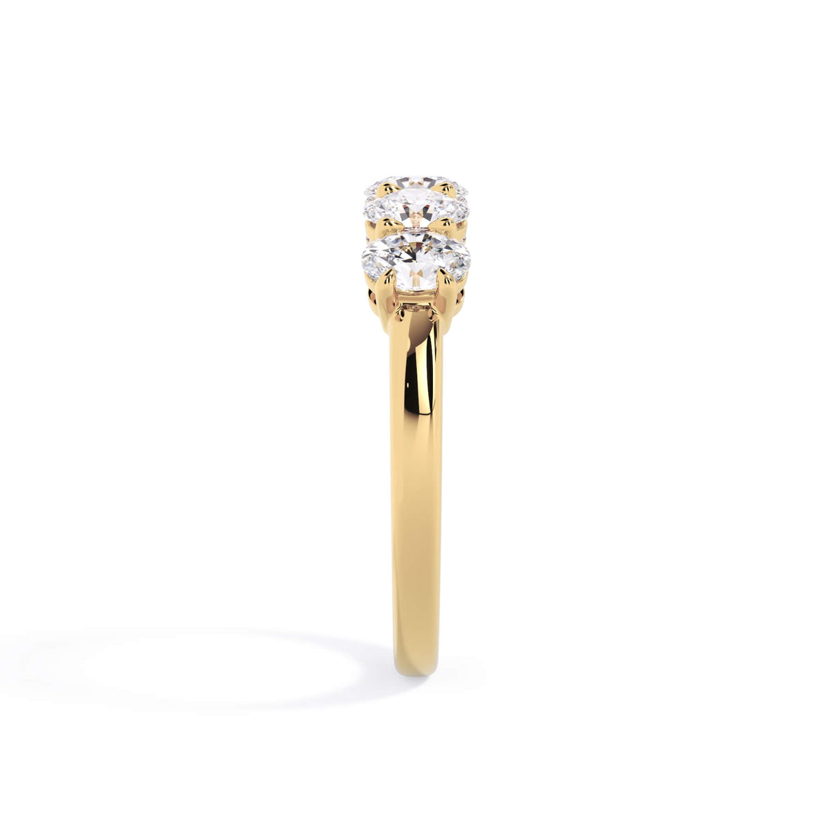 A picture of a five stone diamond wedding ring with oval shape diamonds that are shared prong set in yellow gold on a white background with a side profile view.