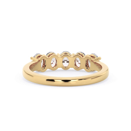 A picture of a five stone diamond wedding ring with oval shape diamonds that are shared prong set in yellow gold on a white background with a view of the underside of the ring.