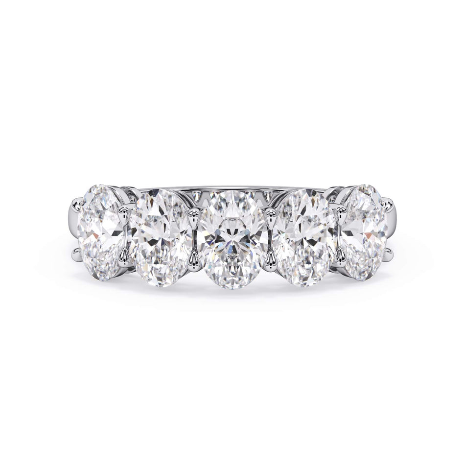 A picture of a five stone diamond wedding ring with oval shape diamonds that are shared prong set in white gold or platinum on a white background with the ring facing forward, lying down.