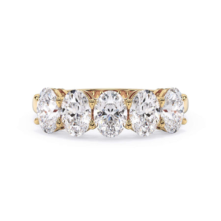 A picture of a five stone diamond wedding ring with oval shape diamonds that are shared prong set in yellow gold on a white background with the ring facing forward, lying down.