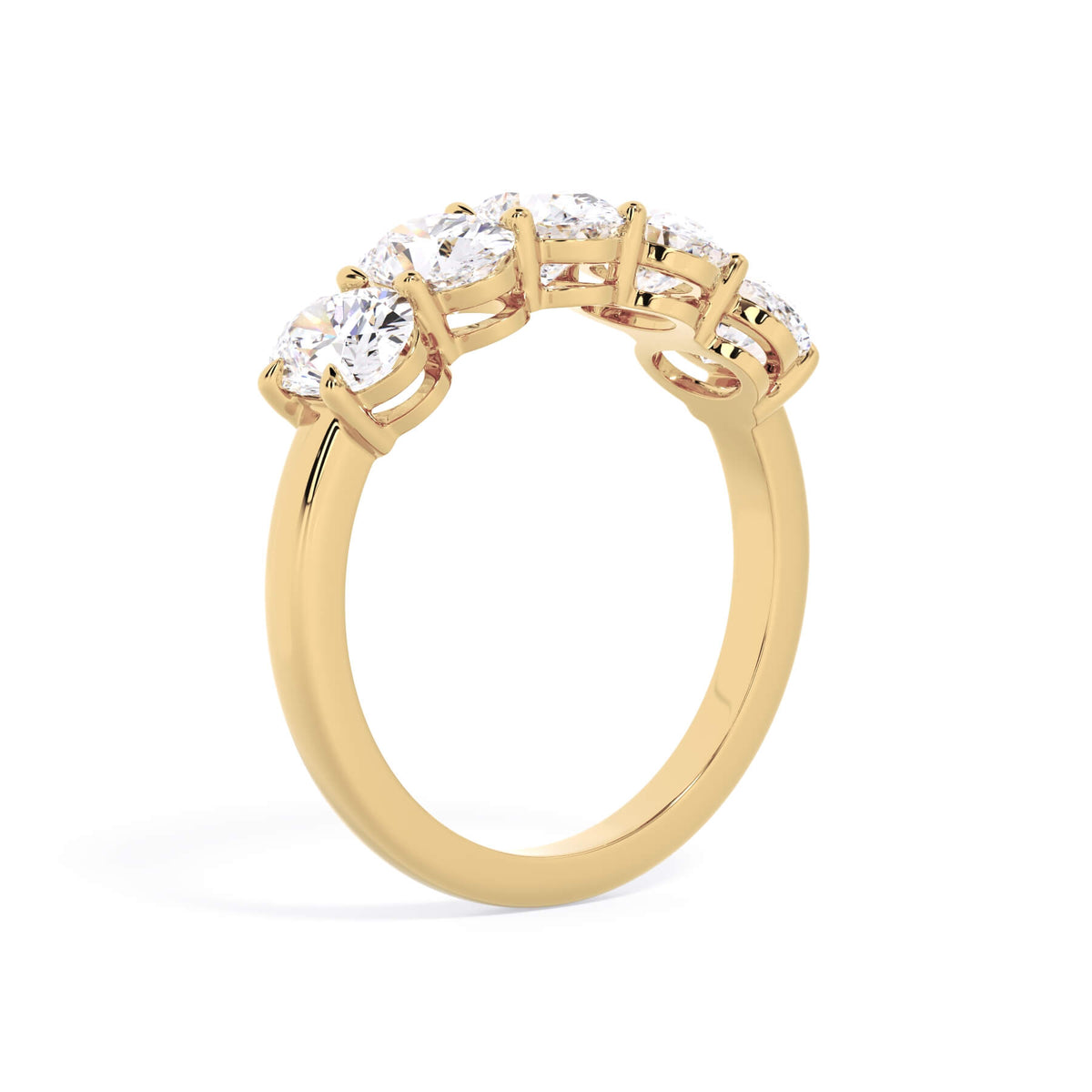 A picture of a five stone diamond wedding ring with oval shape diamonds that are shared prong set in yellow gold on a white background with a slightly angled, through the finger view.