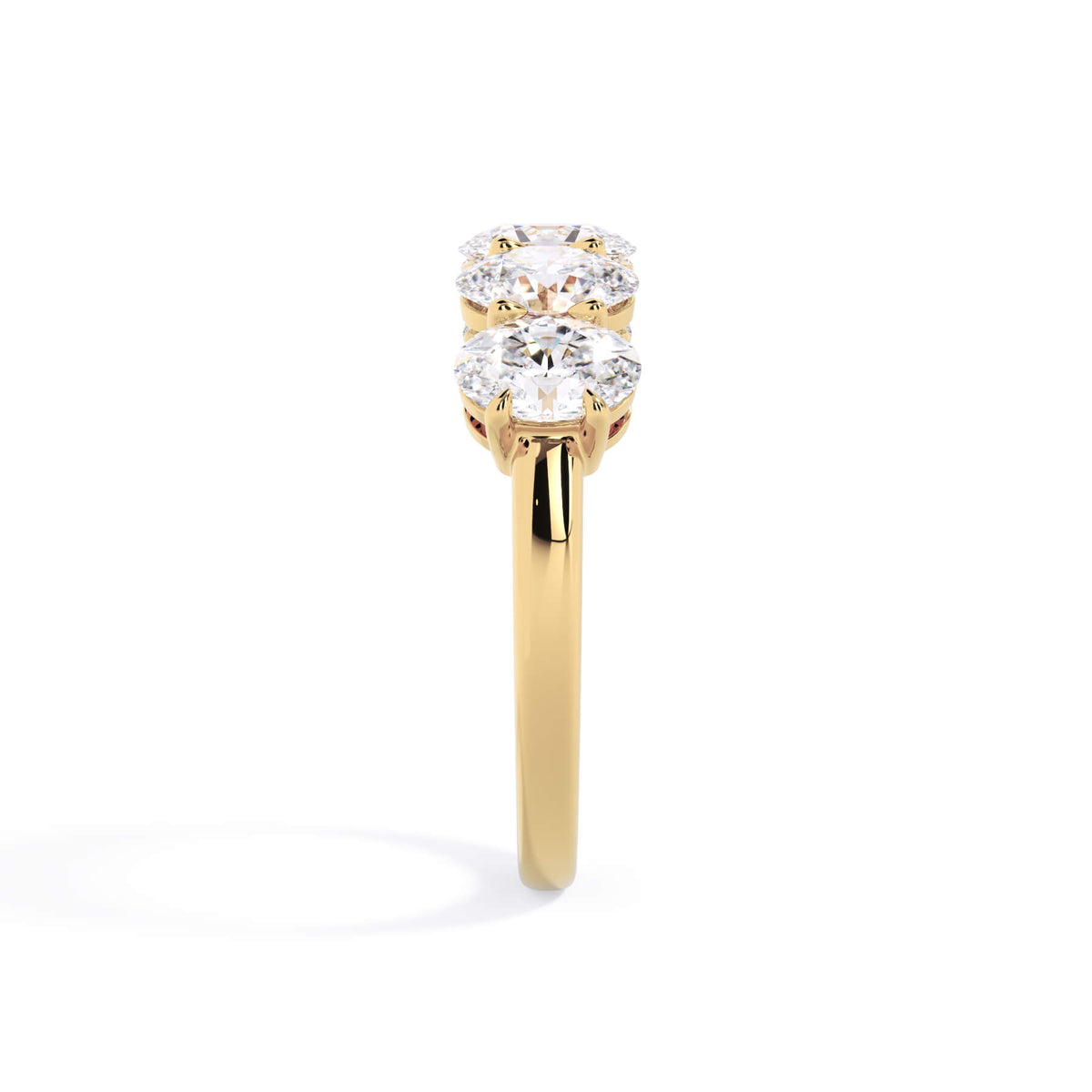 A picture of a five stone diamond wedding ring with oval shape diamonds that are shared prong set in yellow gold on a white background with a side profile view.