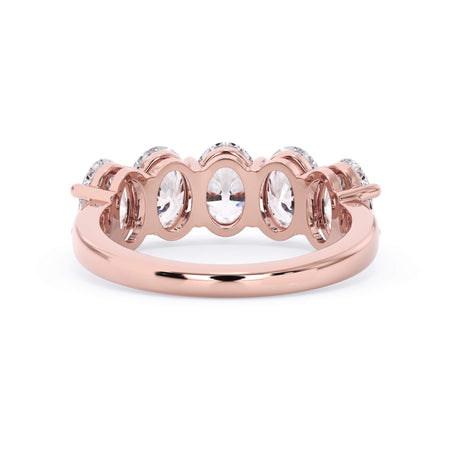 A picture of a five stone diamond wedding ring with oval shape diamonds that are shared prong set in rose gold on a white background with a view of the underside of the ring.