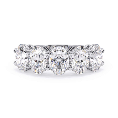 A picture of a five stone diamond wedding ring with oval shape diamonds that are shared prong set in white gold or platinum on a white background with the ring facing forward, lying down.
