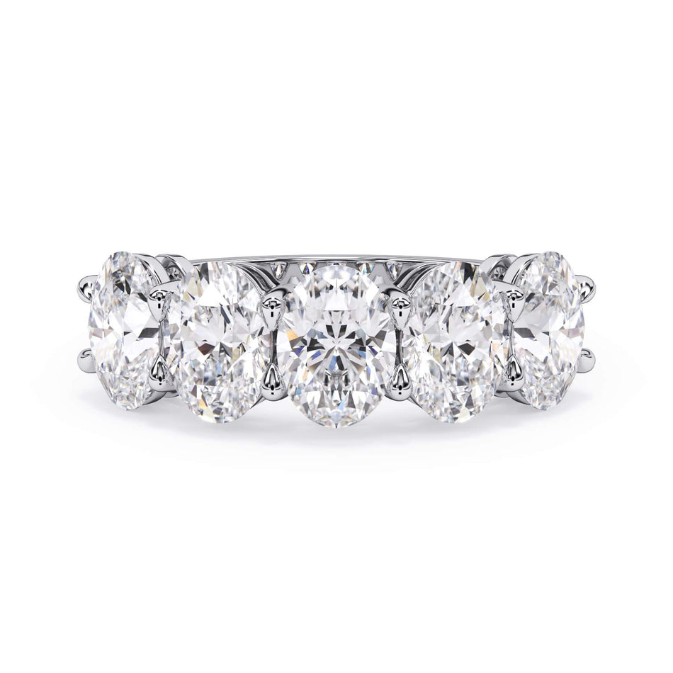 A picture of a five stone diamond wedding ring with oval shape diamonds that are shared prong set in white gold or platinum on a white background with the ring facing forward, lying down.