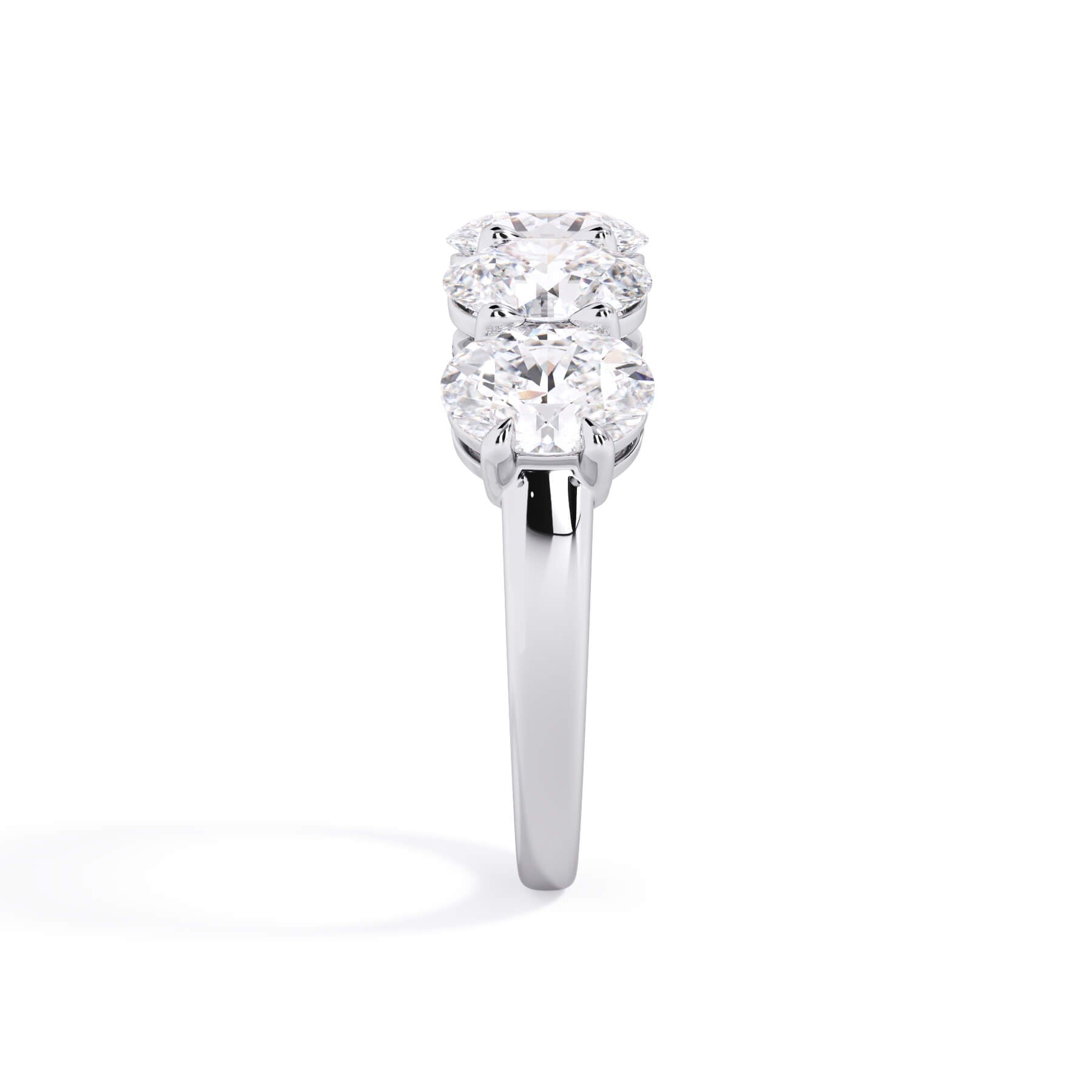 A picture of a five stone diamond wedding ring with oval shape diamonds that are shared prong set in white gold or platinum on a white background with a side profile view.