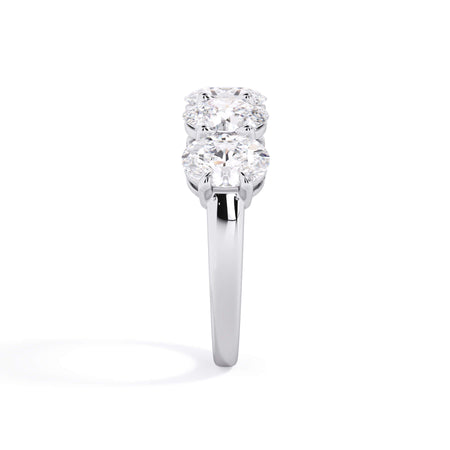 A picture of a five stone diamond wedding ring with oval shape diamonds that are shared prong set in white gold or platinum on a white background with a side profile view.