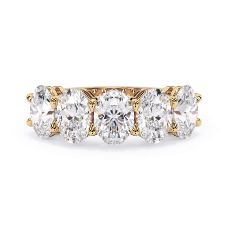 A picture of a five stone diamond wedding ring with oval shape diamonds that are shared prong set in yellow gold on a white background with the ring facing forward, lying down.