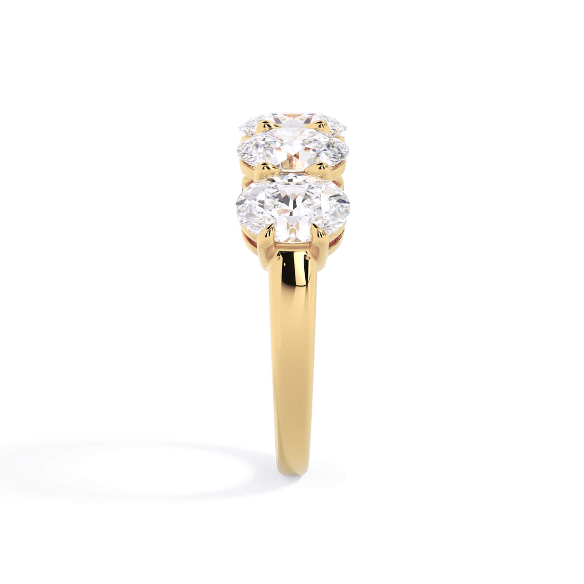 A picture of a five stone diamond wedding ring with oval shape diamonds that are shared prong set in yellow gold on a white background with a side profile view.