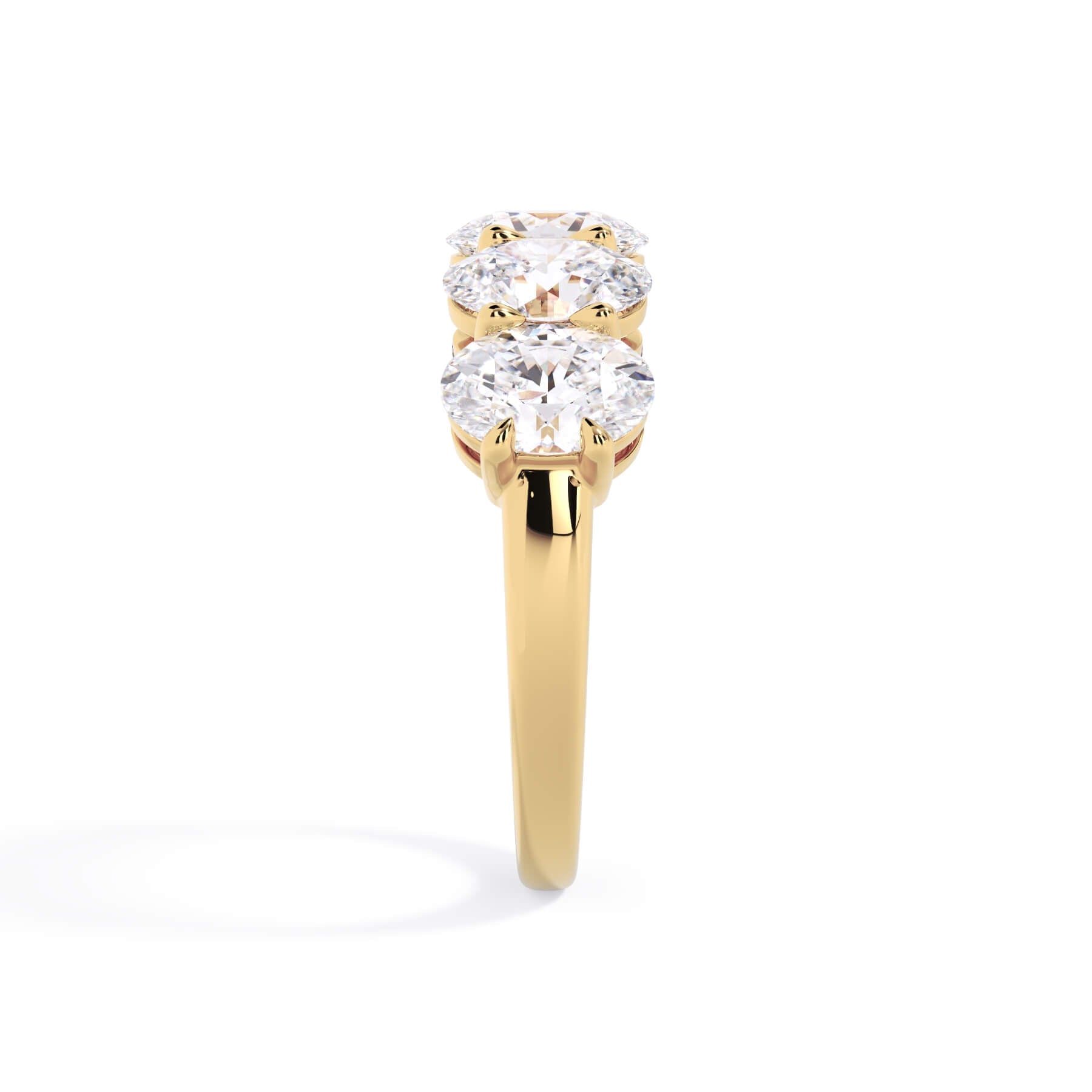A picture of a five stone diamond wedding ring with oval shape diamonds that are shared prong set in yellow gold on a white background with a side profile view.