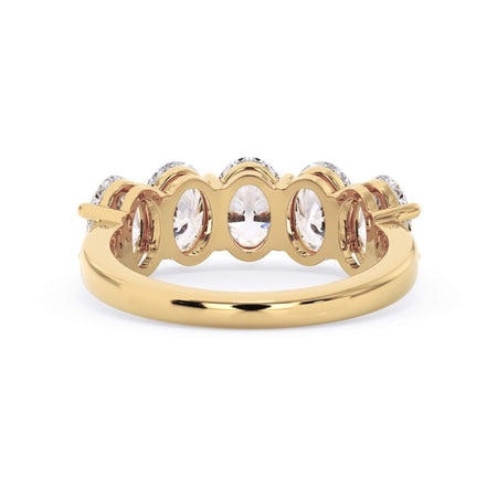 A picture of a five stone diamond wedding ring with oval shape diamonds that are shared prong set in yellow gold on a white background with a view of the underside of the ring.