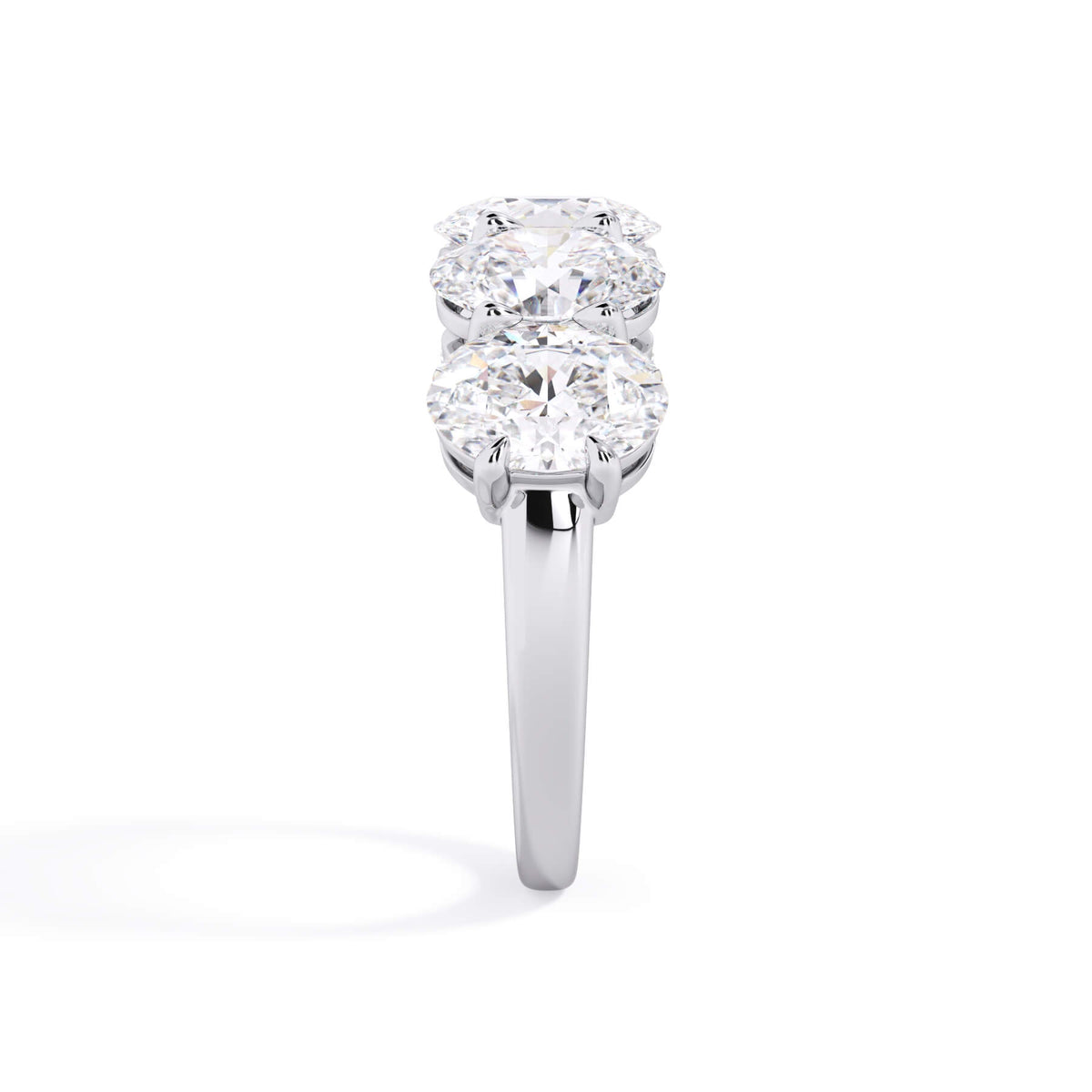 A picture of a five stone diamond wedding ring with oval shape diamonds that are shared prong set in white gold or platinum on a white background with a side profile view.