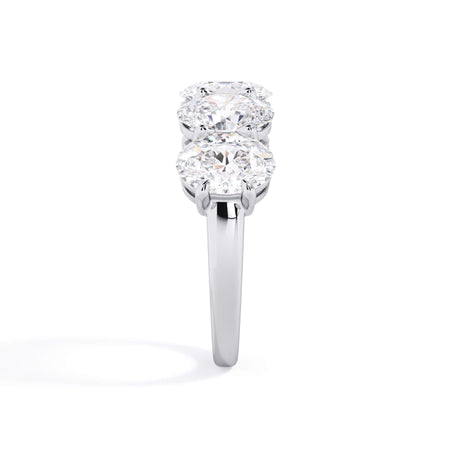A picture of a five stone diamond wedding ring with oval shape diamonds that are shared prong set in white gold or platinum on a white background with a side profile view.
