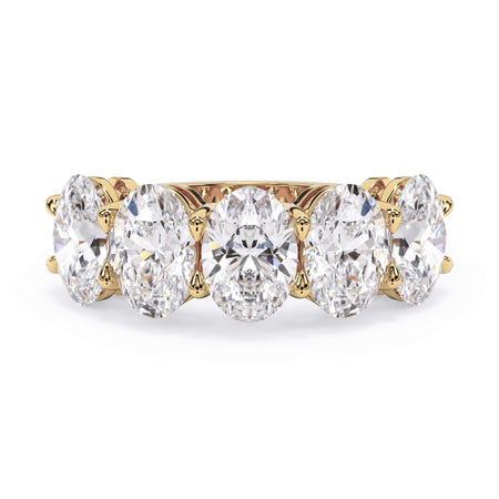 A picture of a five stone diamond wedding ring with oval shape diamonds that are shared prong set in yellow gold on a white background with the ring facing forward, lying down.
