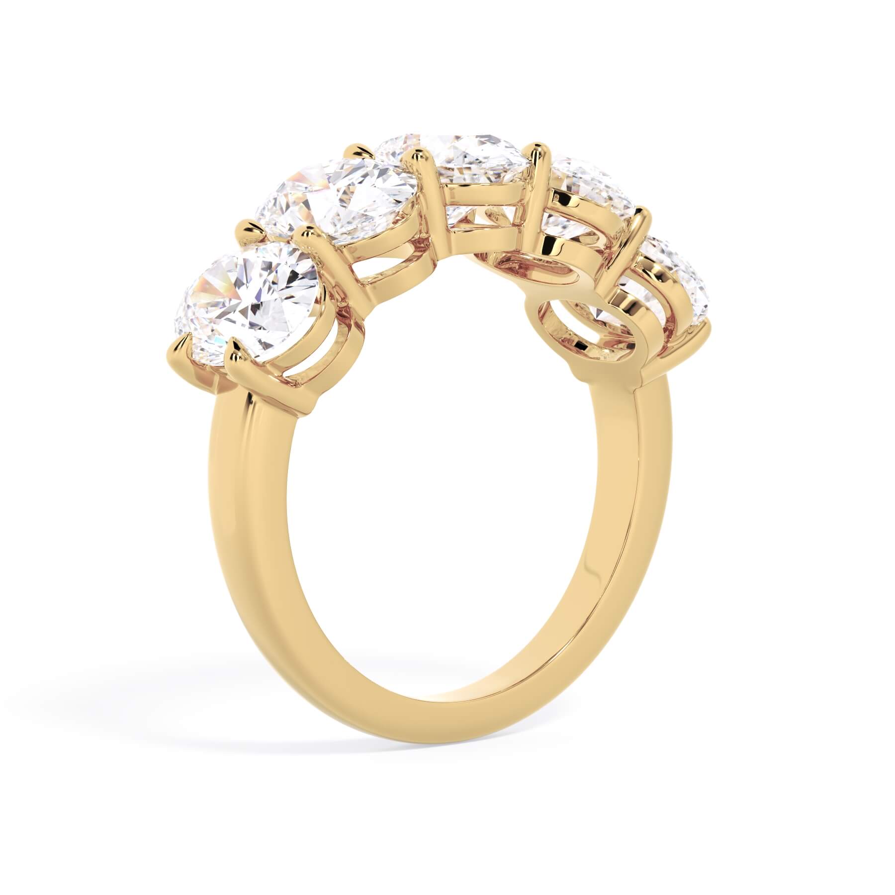 A picture of a five stone diamond wedding ring with oval shape diamonds that are shared prong set in yellow gold on a white background with a slightly angled, through the finger view.