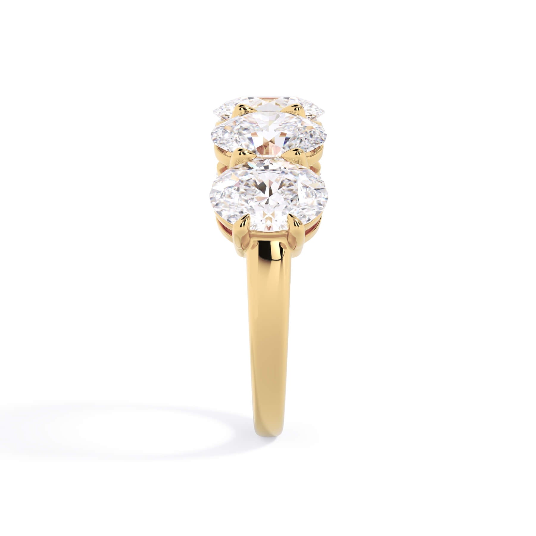 A picture of a five stone diamond wedding ring with oval shape diamonds that are shared prong set in yellow gold on a white background with a side profile view.