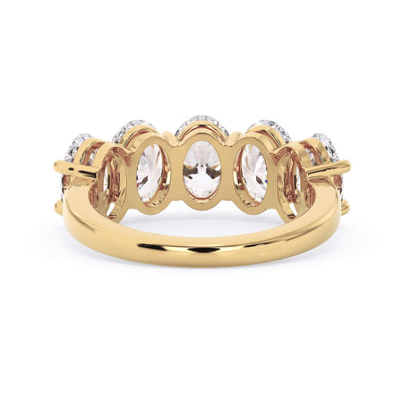 A picture of a five stone diamond wedding ring with oval shape diamonds that are shared prong set in yellow gold on a white background with a view of the underside of the ring.