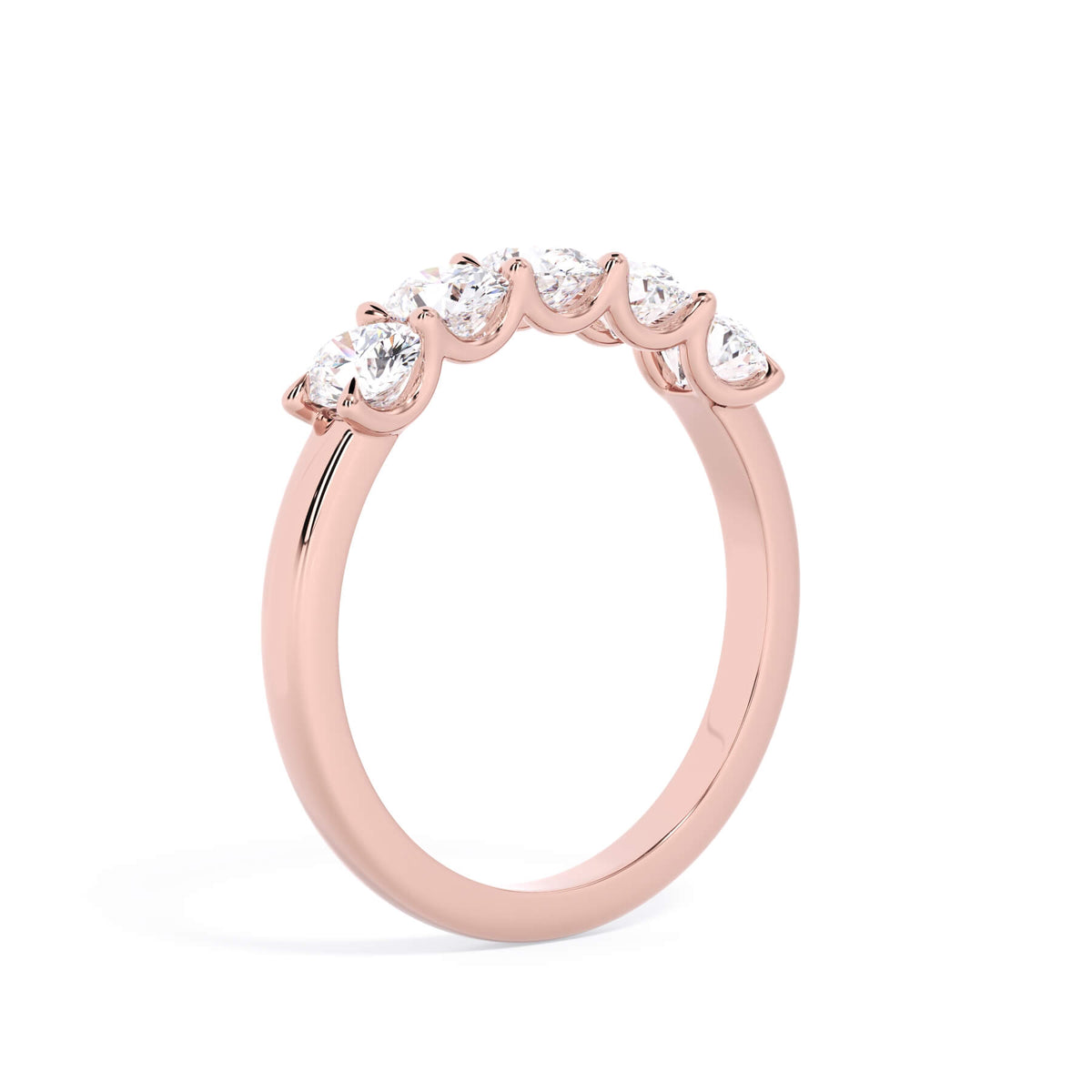 A picture of a five stone diamond wedding ring with oval shape diamonds that are u prong set in rose gold on a white background with a slightly angled, through the finger view.