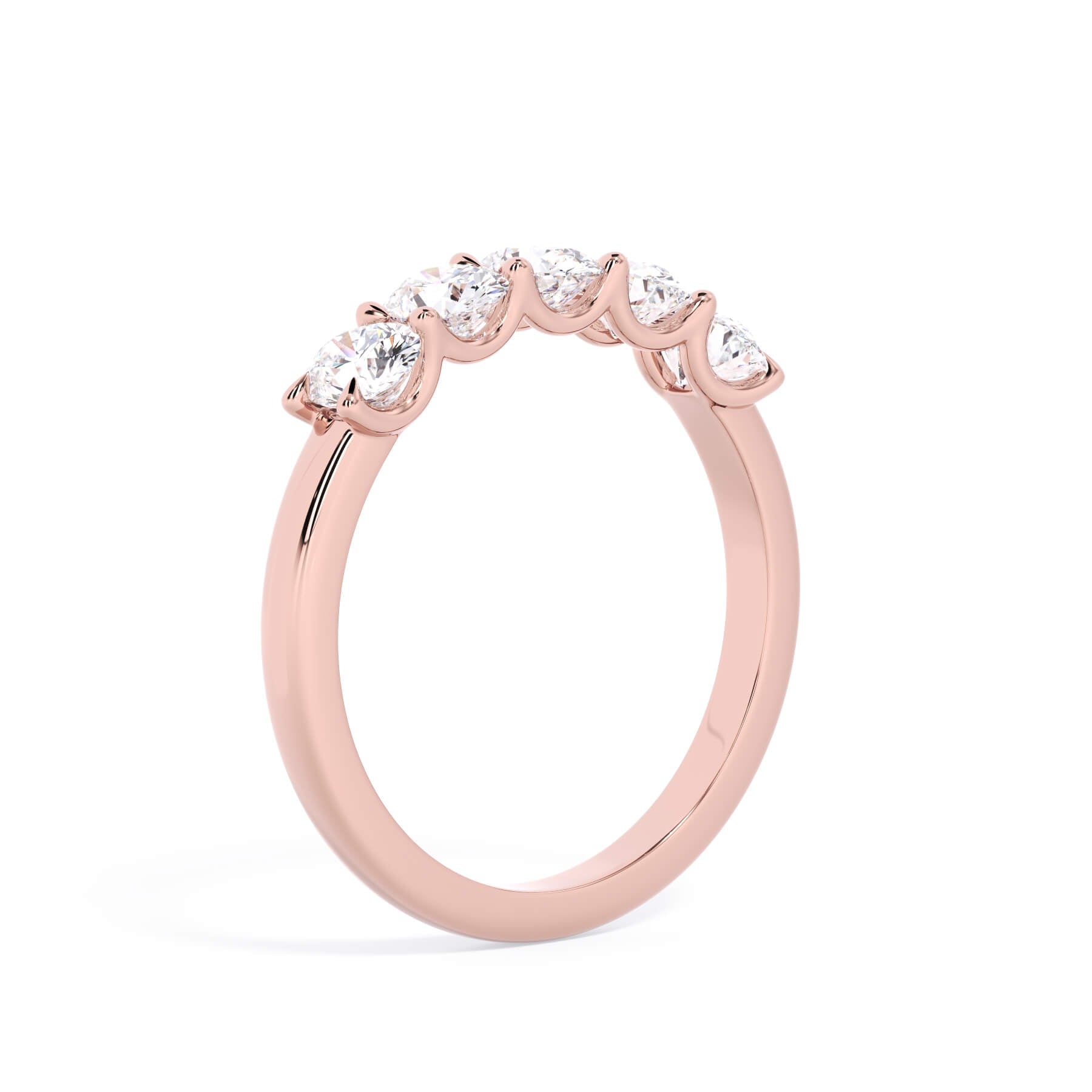 A picture of a five stone diamond wedding ring with oval shape diamonds that are u prong set in rose gold on a white background with a slightly angled, through the finger view.