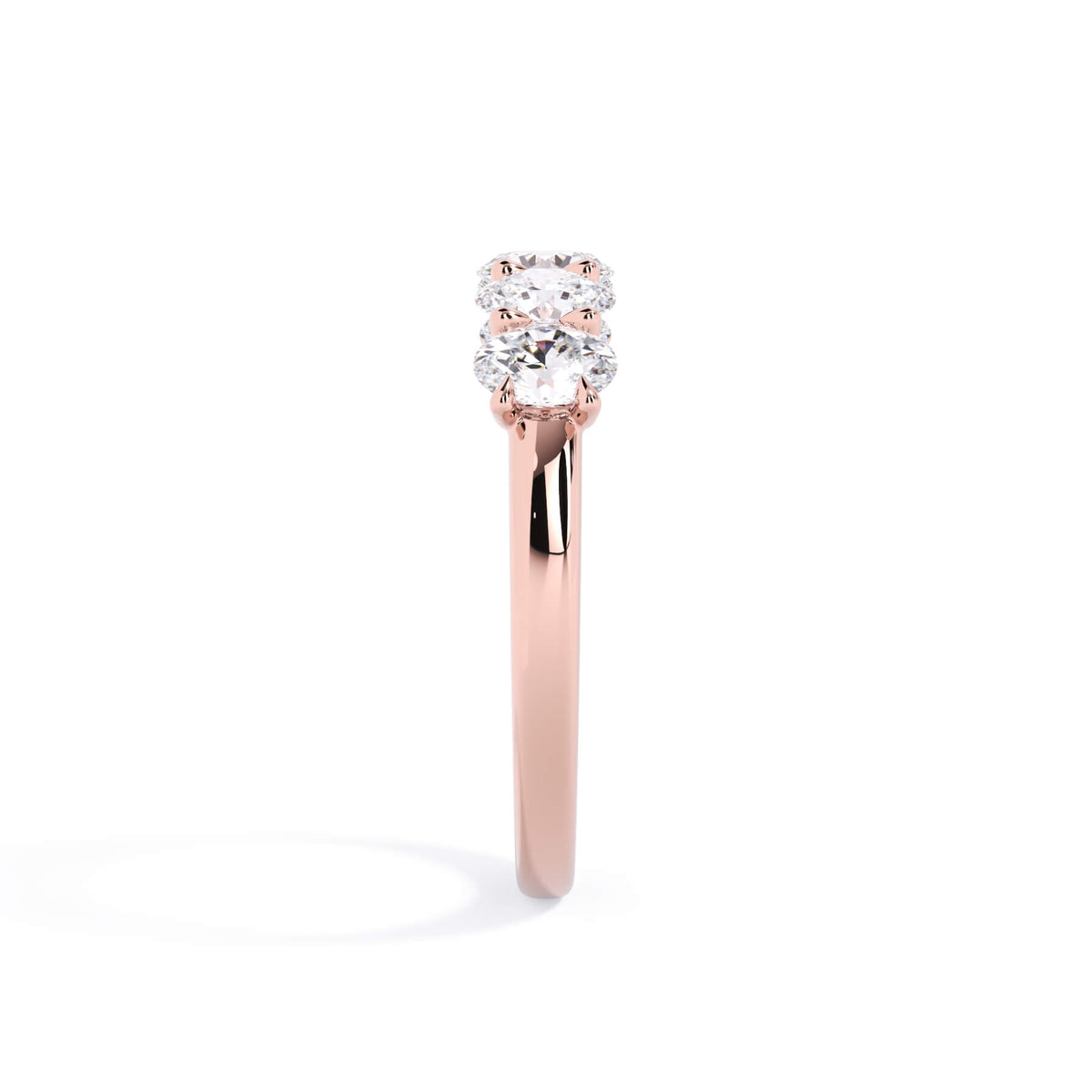 A picture of a five stone diamond wedding ring with oval shape diamonds that are u prong set in rose gold on a white background with a side profile view.