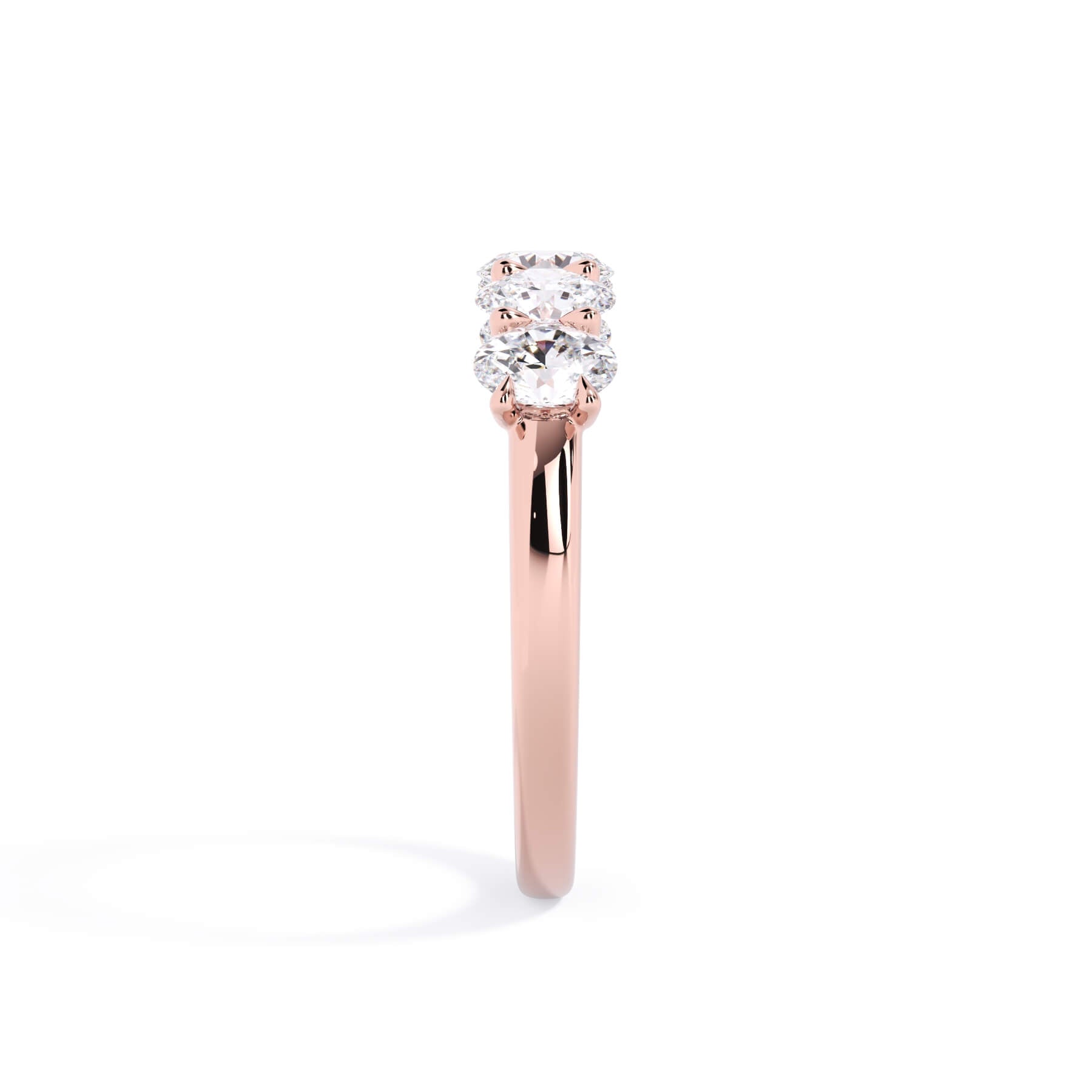 A picture of a five stone diamond wedding ring with oval shape diamonds that are u prong set in rose gold on a white background with a side profile view.