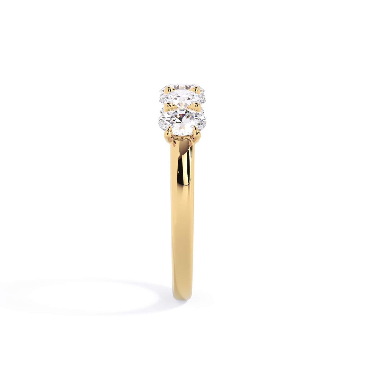 A picture of a five stone diamond wedding ring with oval shape diamonds that are u prong set in yellow gold on a white background with a side profile view.