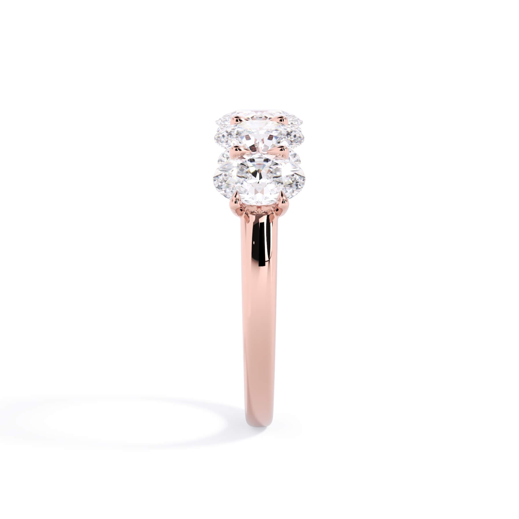 A picture of a five stone diamond wedding ring with oval shape diamonds that are u prong set in rose gold on a white background with a side profile view.
