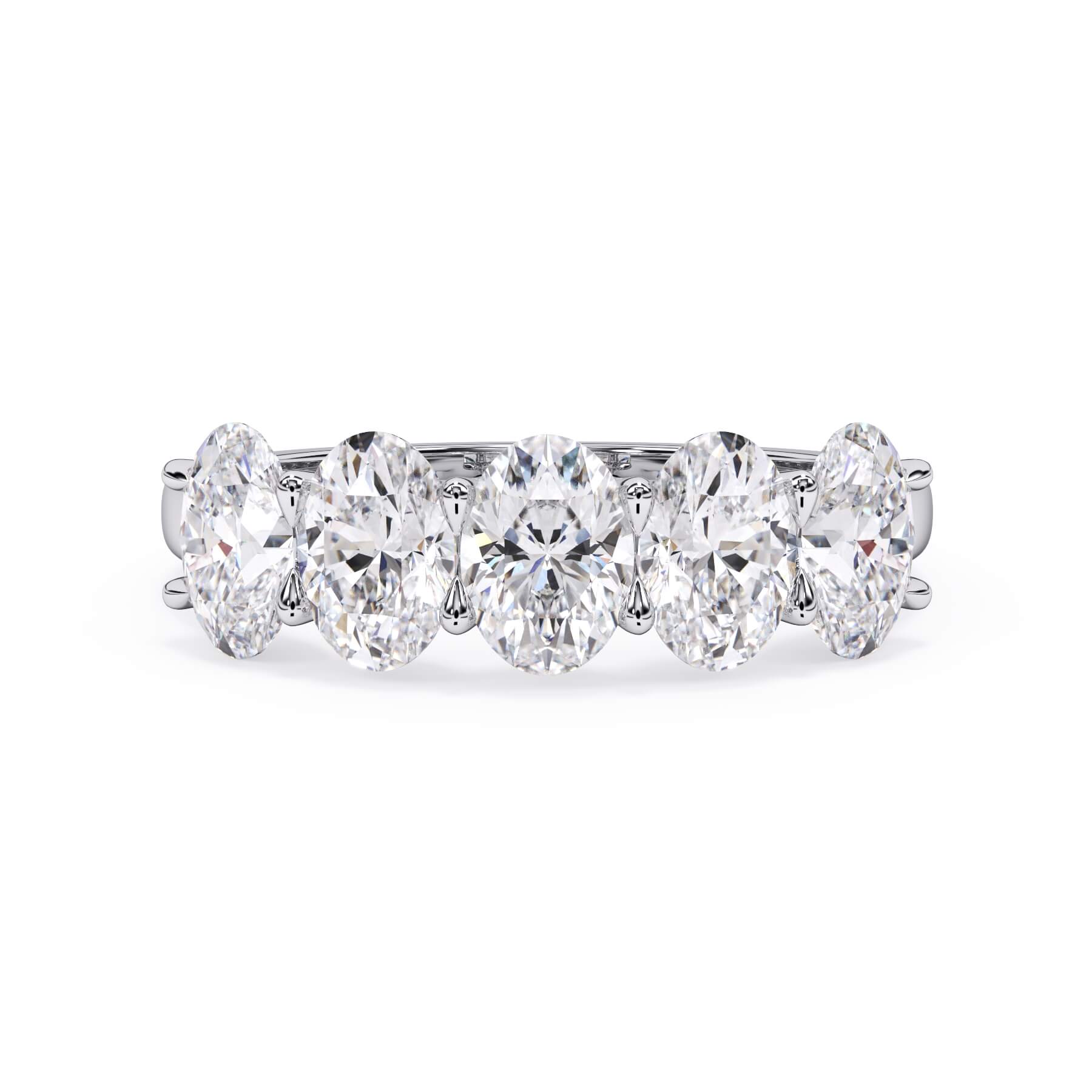 A picture of a five stone diamond wedding ring with oval shape diamonds that are u prong set in white gold or platinum on a white background with the ring facing forward, lying down.