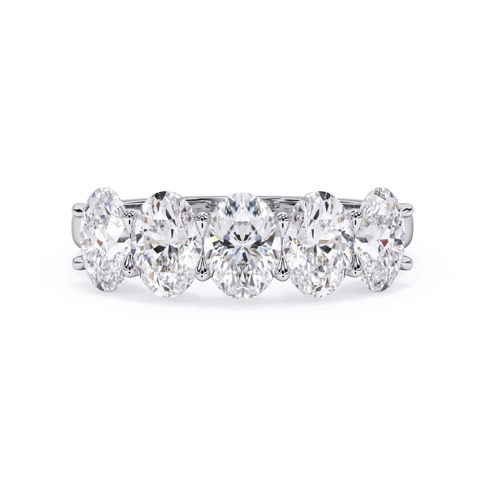 A picture of a five stone diamond wedding ring with oval shape diamonds that are u prong set in white gold or platinum on a white background with the ring facing forward, lying down.