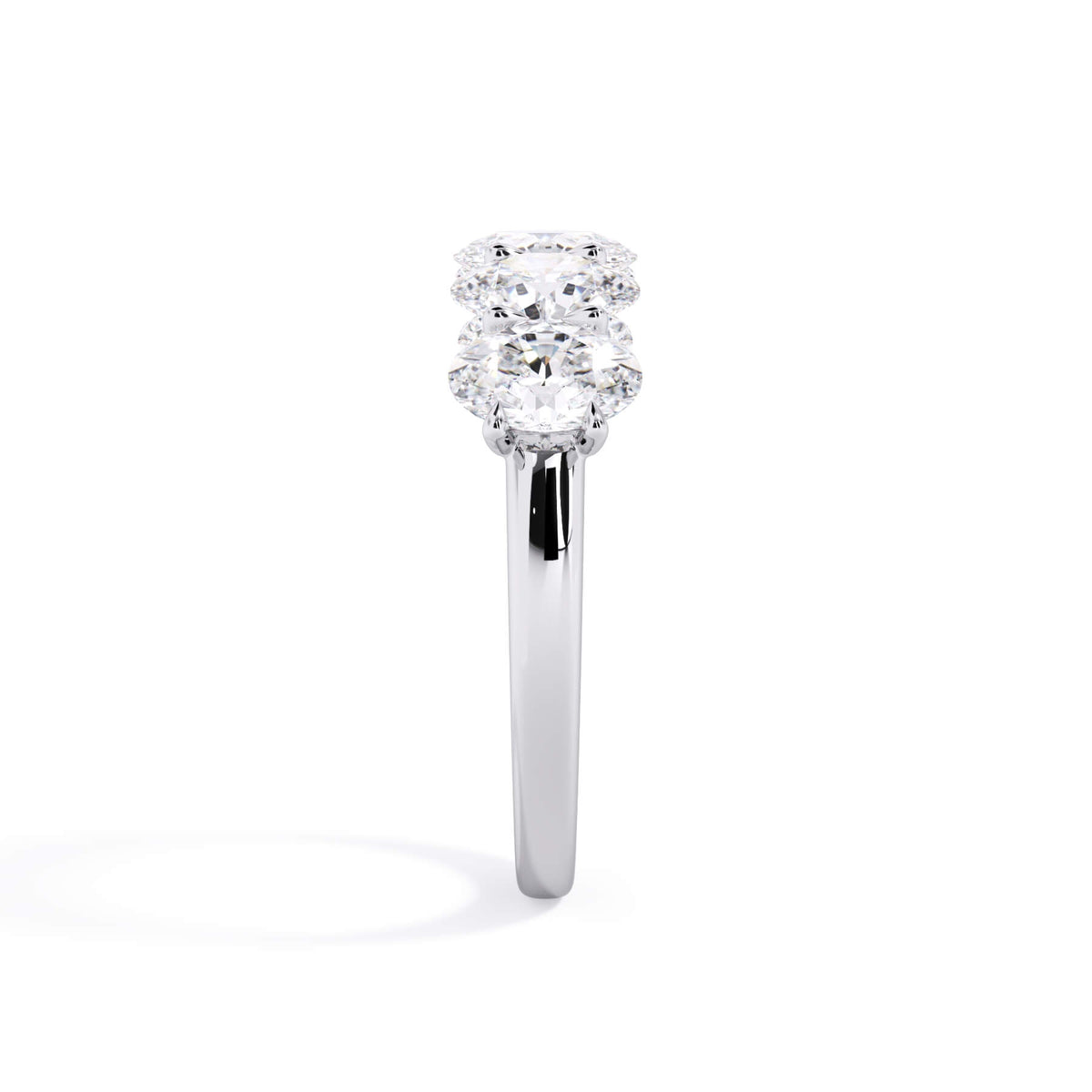A picture of a five stone diamond wedding ring with oval shape diamonds that are u prong set in white gold or platinum on a white background with a side profile view.