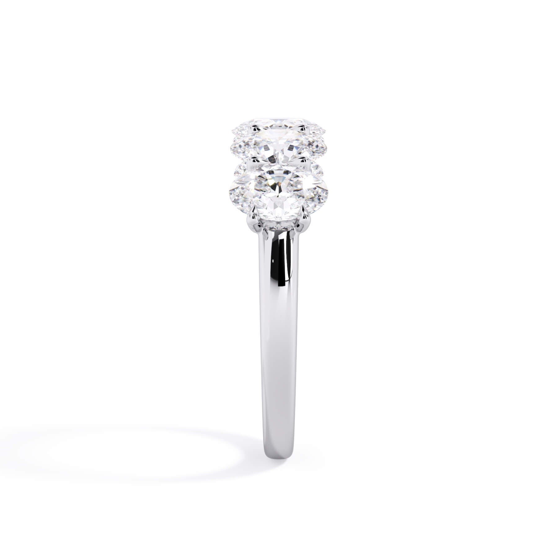 A picture of a five stone diamond wedding ring with oval shape diamonds that are u prong set in white gold or platinum on a white background with a side profile view.
