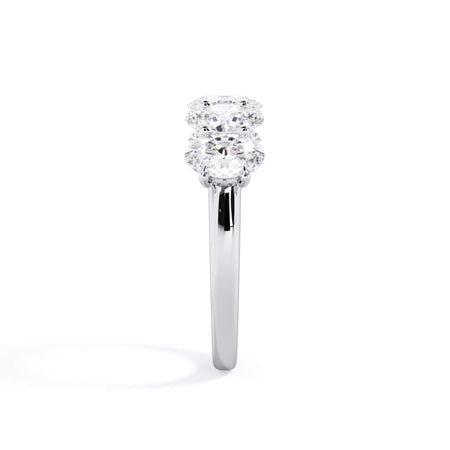 A picture of a five stone diamond wedding ring with oval shape diamonds that are u prong set in white gold or platinum on a white background with a side profile view.