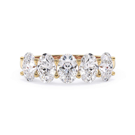 A picture of a five stone diamond wedding ring with oval shape diamonds that are u prong set in yellow gold on a white background with the ring facing forward, lying down.