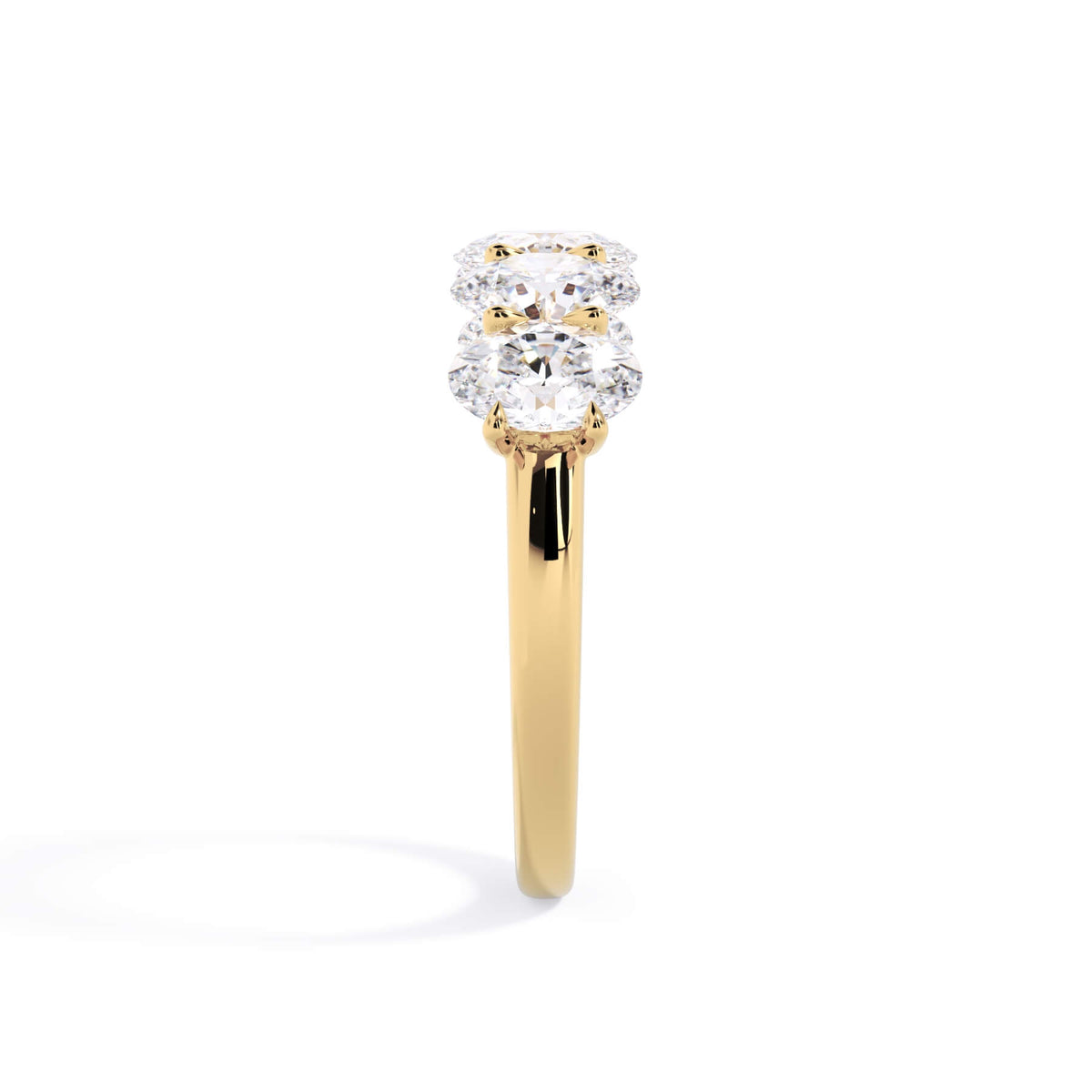 A picture of a five stone diamond wedding ring with oval shape diamonds that are u prong set in yellow gold on a white background with a side profile view.