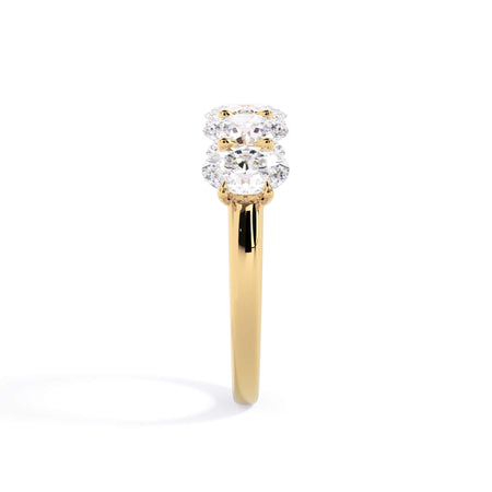 A picture of a five stone diamond wedding ring with oval shape diamonds that are u prong set in yellow gold on a white background with a side profile view.