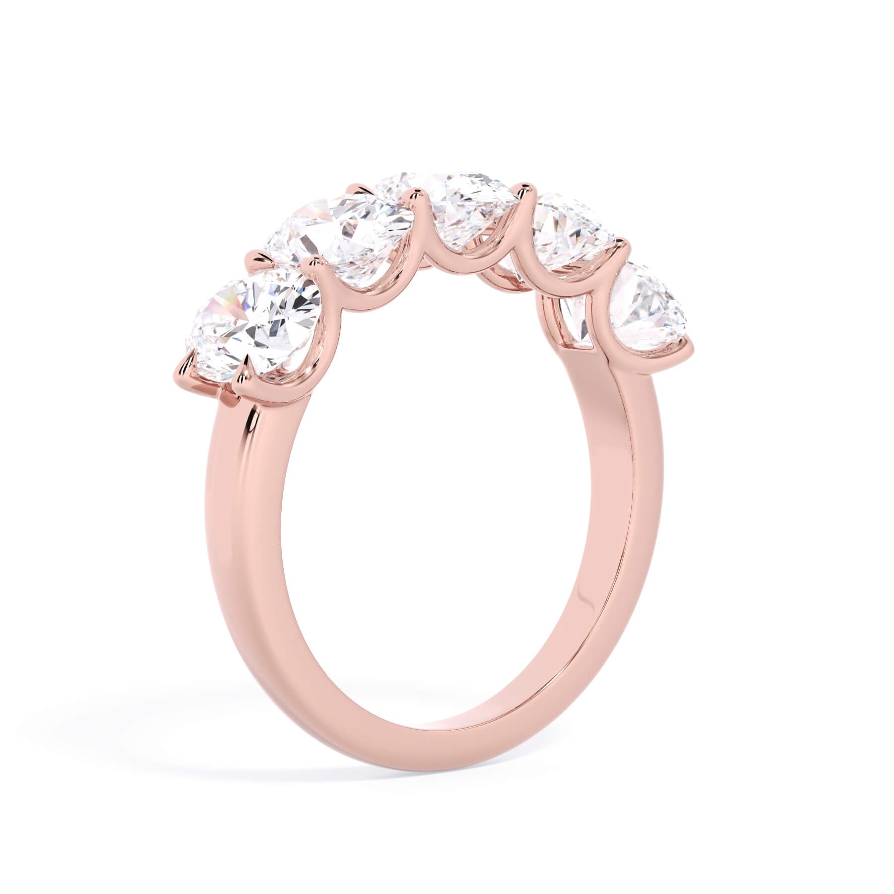 A picture of a five stone diamond wedding ring with oval shape diamonds that are u prong set in rose gold on a white background with a slightly angled, through the finger view.