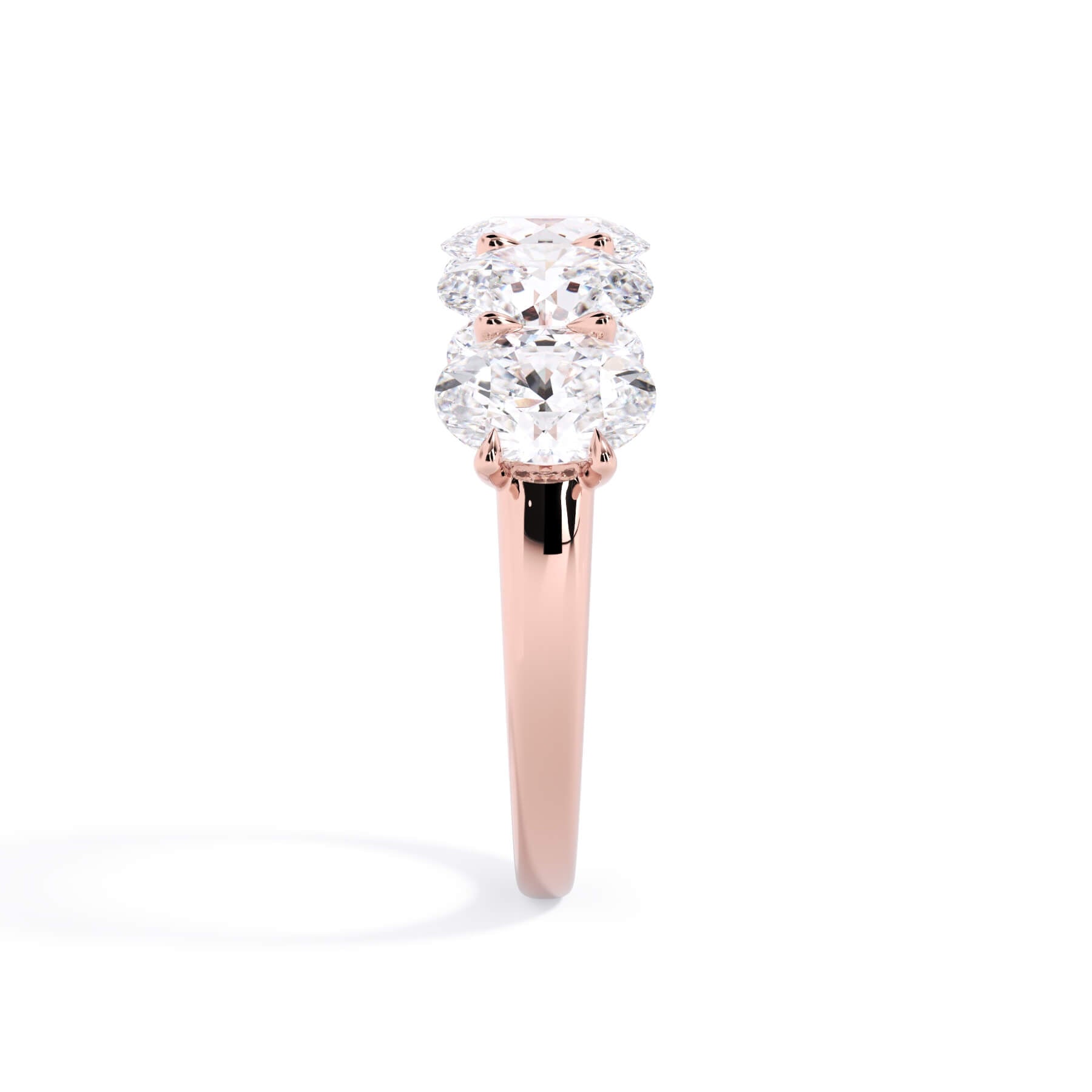 A picture of a five stone diamond wedding ring with oval shape diamonds that are u prong set in rose gold on a white background with a side profile view.