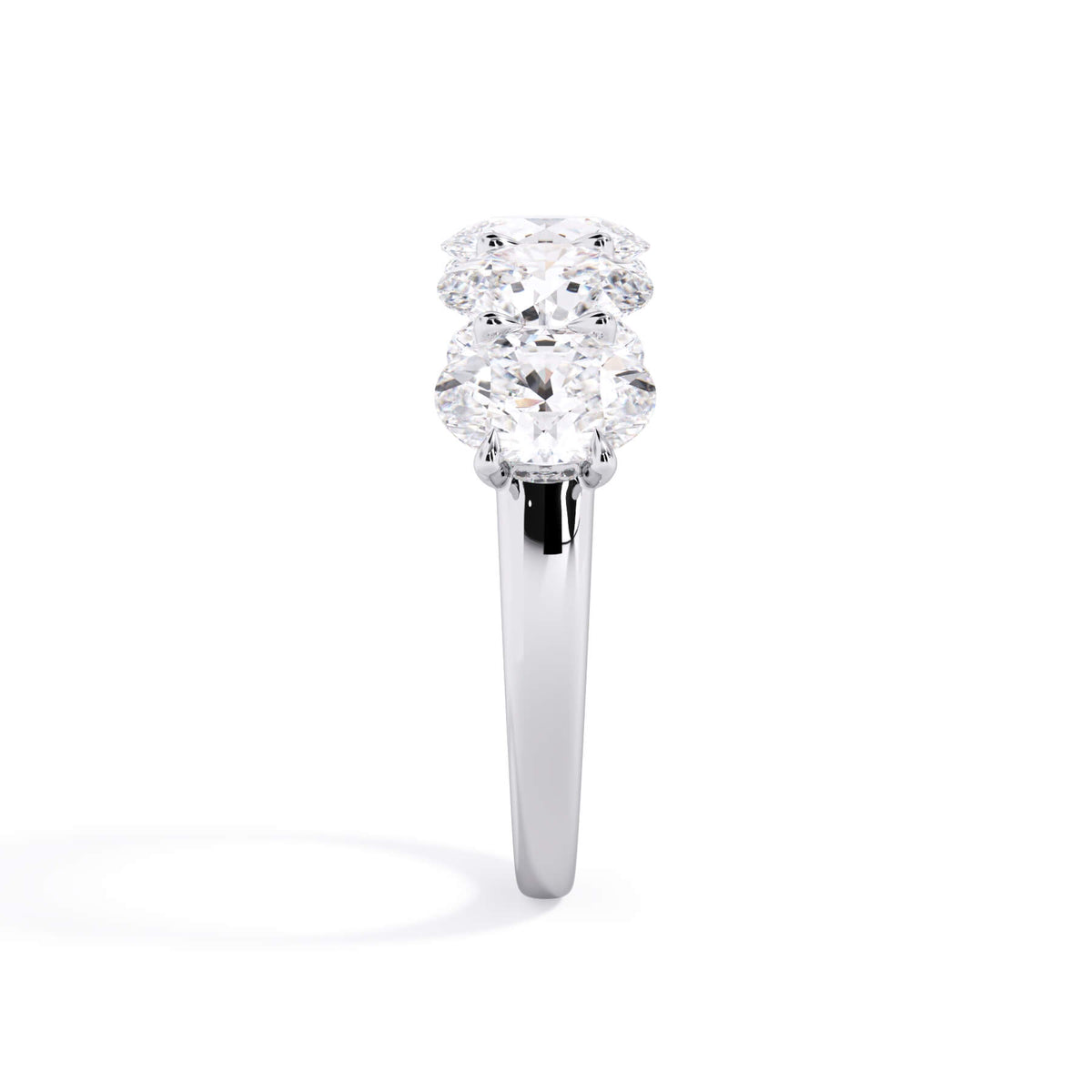 A picture of a five stone diamond wedding ring with oval shape diamonds that are u prong set in white gold or platinum on a white background with a side profile view.