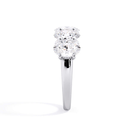 A picture of a five stone diamond wedding ring with oval shape diamonds that are u prong set in white gold or platinum on a white background with a side profile view.