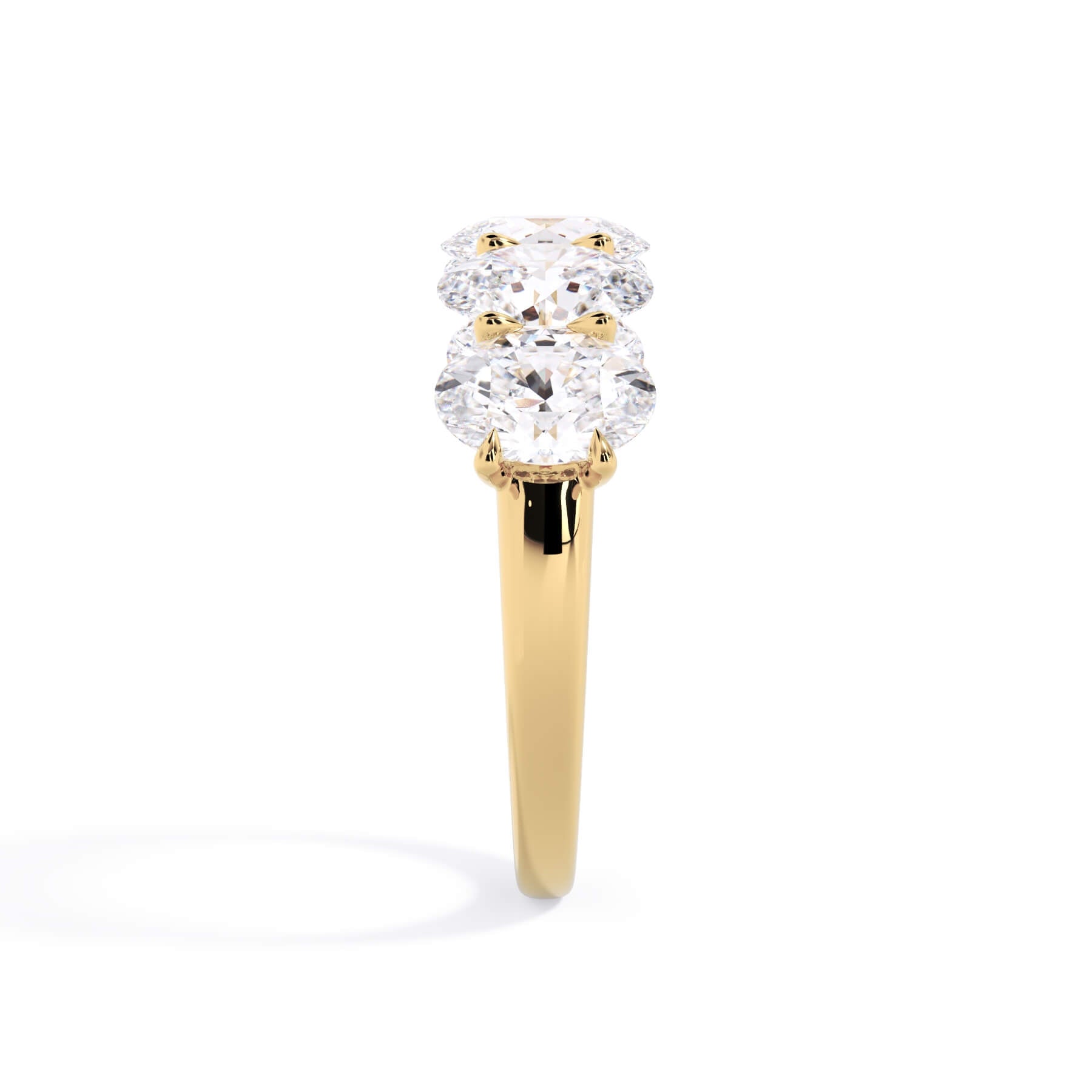 A picture of a five stone diamond wedding ring with oval shape diamonds that are u prong set in yellow gold on a white background with a side profile view.