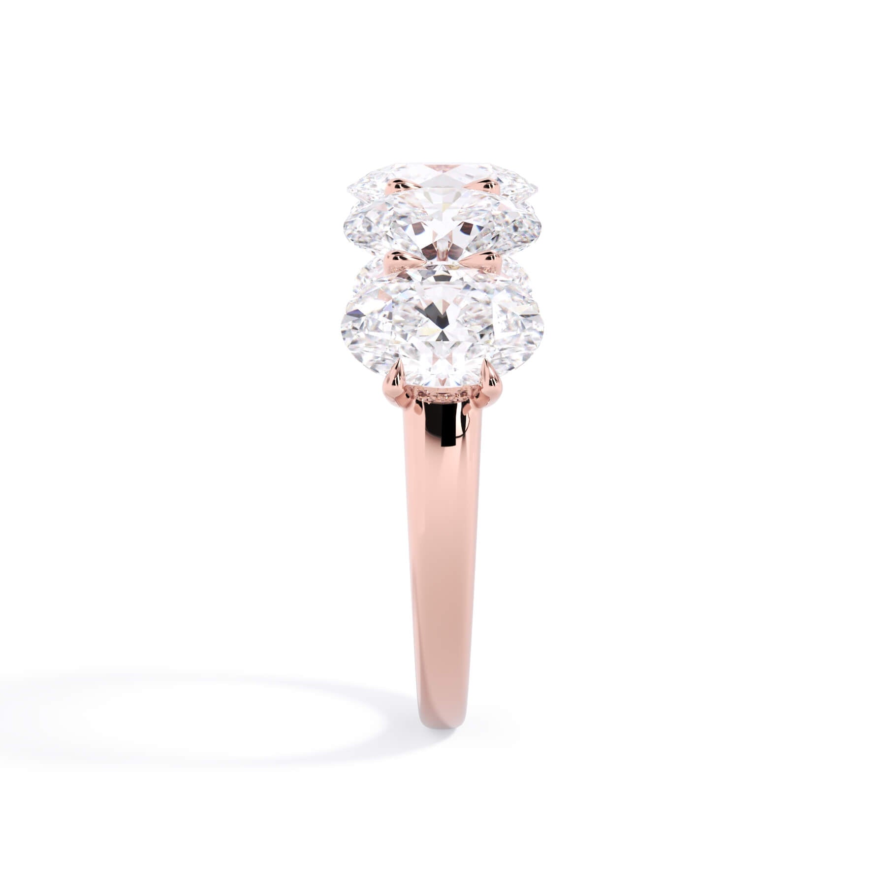 A picture of a five stone diamond wedding ring with oval shape diamonds that are u prong set in rose gold on a white background with a side profile view.