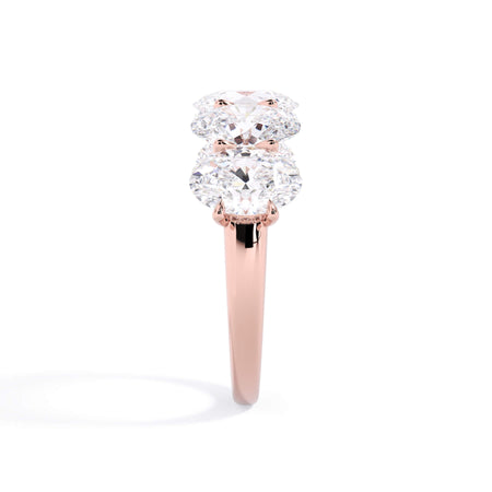 A picture of a five stone diamond wedding ring with oval shape diamonds that are u prong set in rose gold on a white background with a side profile view.