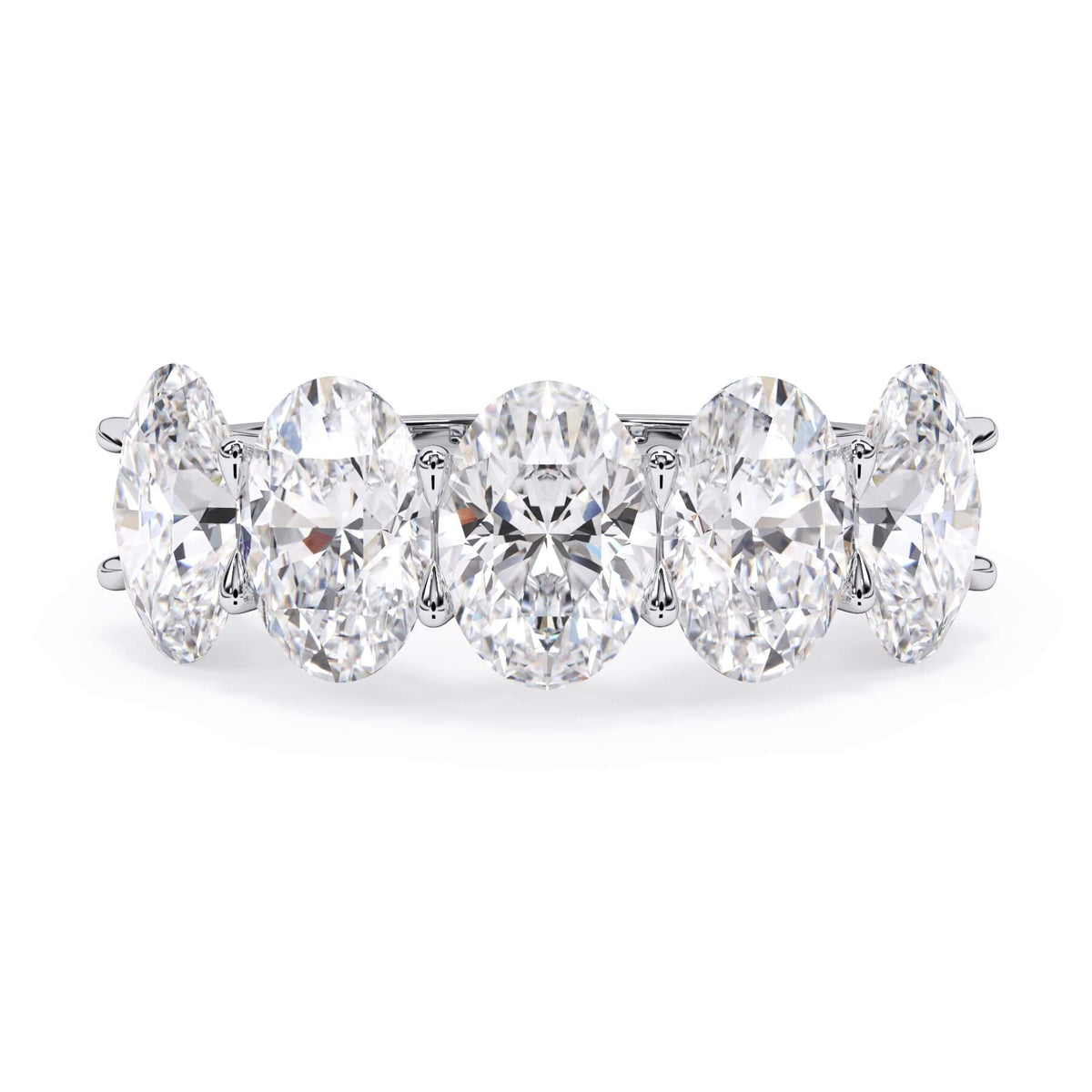 A picture of a five stone diamond wedding ring with oval shape diamonds that are u prong set in white gold or platinum on a white background with the ring facing forward, lying down.