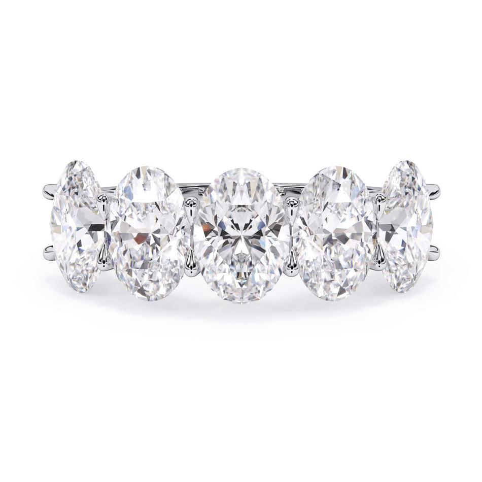 A picture of a five stone diamond wedding ring with oval shape diamonds that are u prong set in white gold or platinum on a white background with the ring facing forward, lying down.