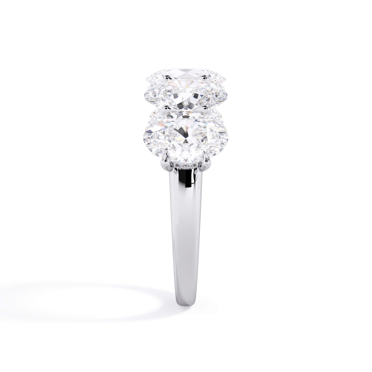 A picture of a five stone diamond wedding ring with oval shape diamonds that are u prong set in white gold or platinum on a white background with a side profile view.