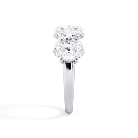 A picture of a five stone diamond wedding ring with oval shape diamonds that are u prong set in white gold or platinum on a white background with a side profile view.