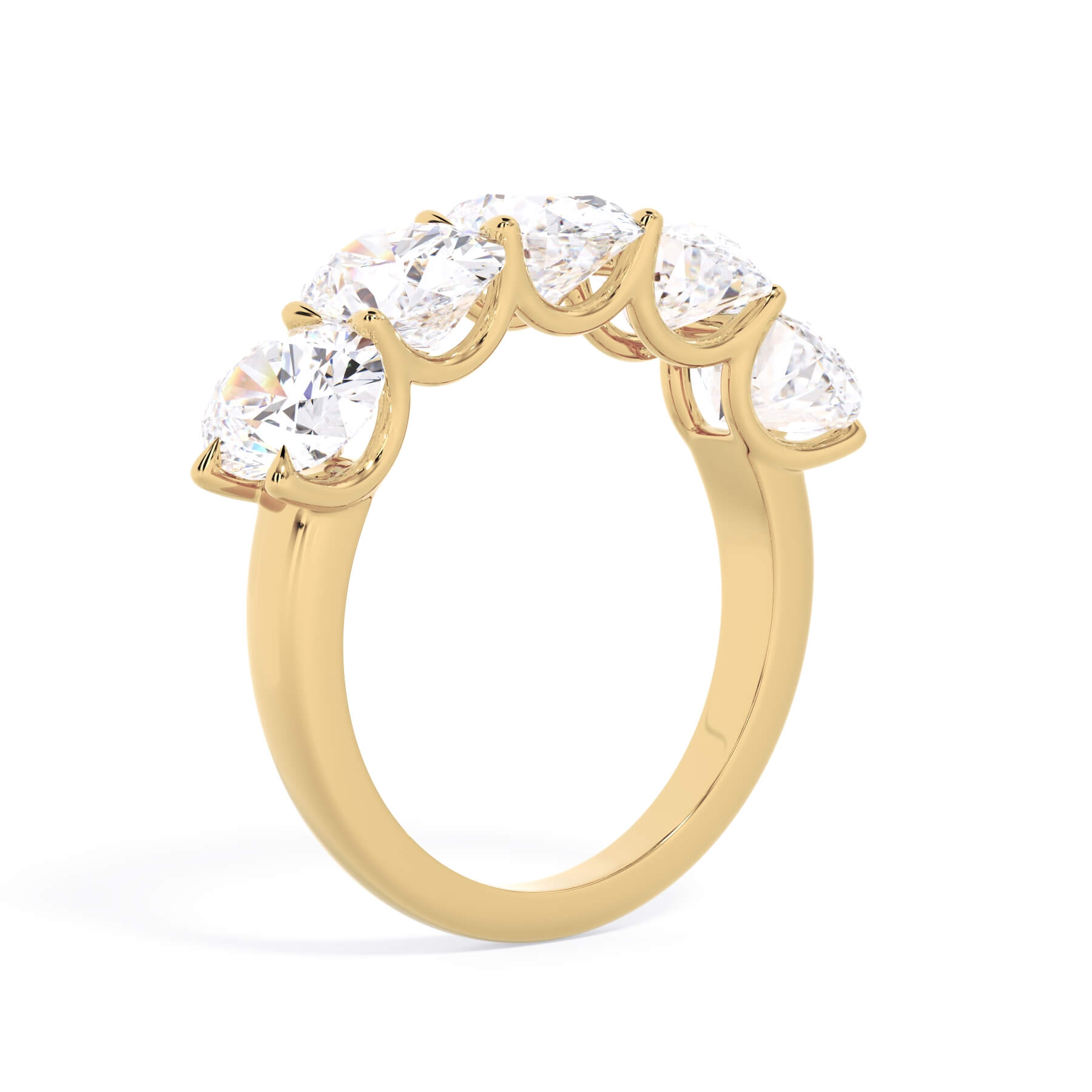 A picture of a five stone diamond wedding ring with oval shape diamonds that are u prong set in yellow gold on a white background with a slightly angled, through the finger view.