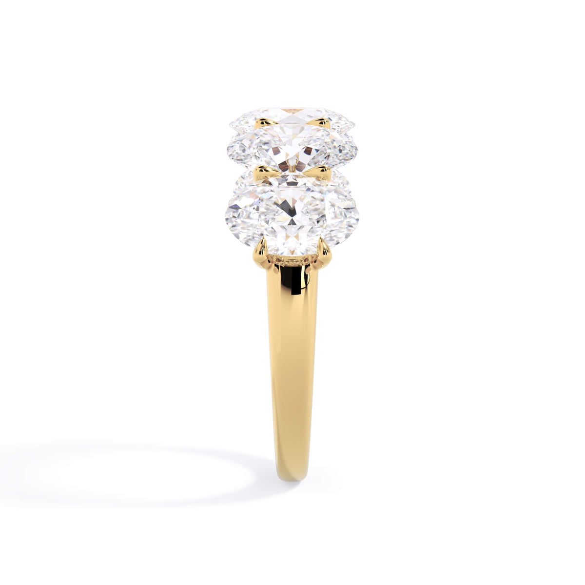 A picture of a five stone diamond wedding ring with oval shape diamonds that are u prong set in yellow gold on a white background with a side profile view.