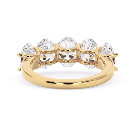 A picture of a five stone diamond wedding ring with oval shape diamonds that are u prong set in yellow gold on a white background with a view of the underside of the ring.