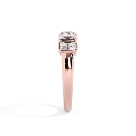 A picture of a five stone diamond wedding ring with radiant cut diamonds that are bezel set in rose gold on a white background with a side profile view.